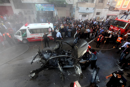 Palestinian firefighters extinguish the car of Ahmad al-Jabari, head of the military wing of the Hamas movement, after it was hit in an Israeli air strike in Gaza City, 14 November