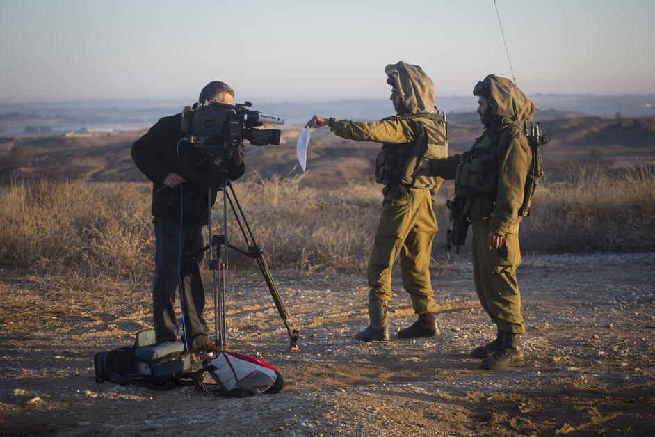Israeli soldiers display a military order to a cameraman in southern Israel to prevent him from filming Gaza