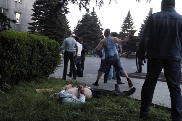 Youri Nikolenko, 48 ans, au centre, en tee-shirt bleu, jette une pierre au moment où les miliciens se replient dans leurs camionnettes.
