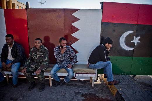 Libyans in Benghazi last year in front of a Libyan flag, right, and a Qatari flag painted on the wall.