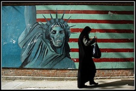 Iran, une femme marche le long d'un mur, où la statue de la liberté est un squelette
