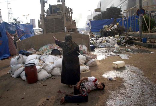Une Egyptienne se tient devant un bulldozer des forces de l'ordre. 